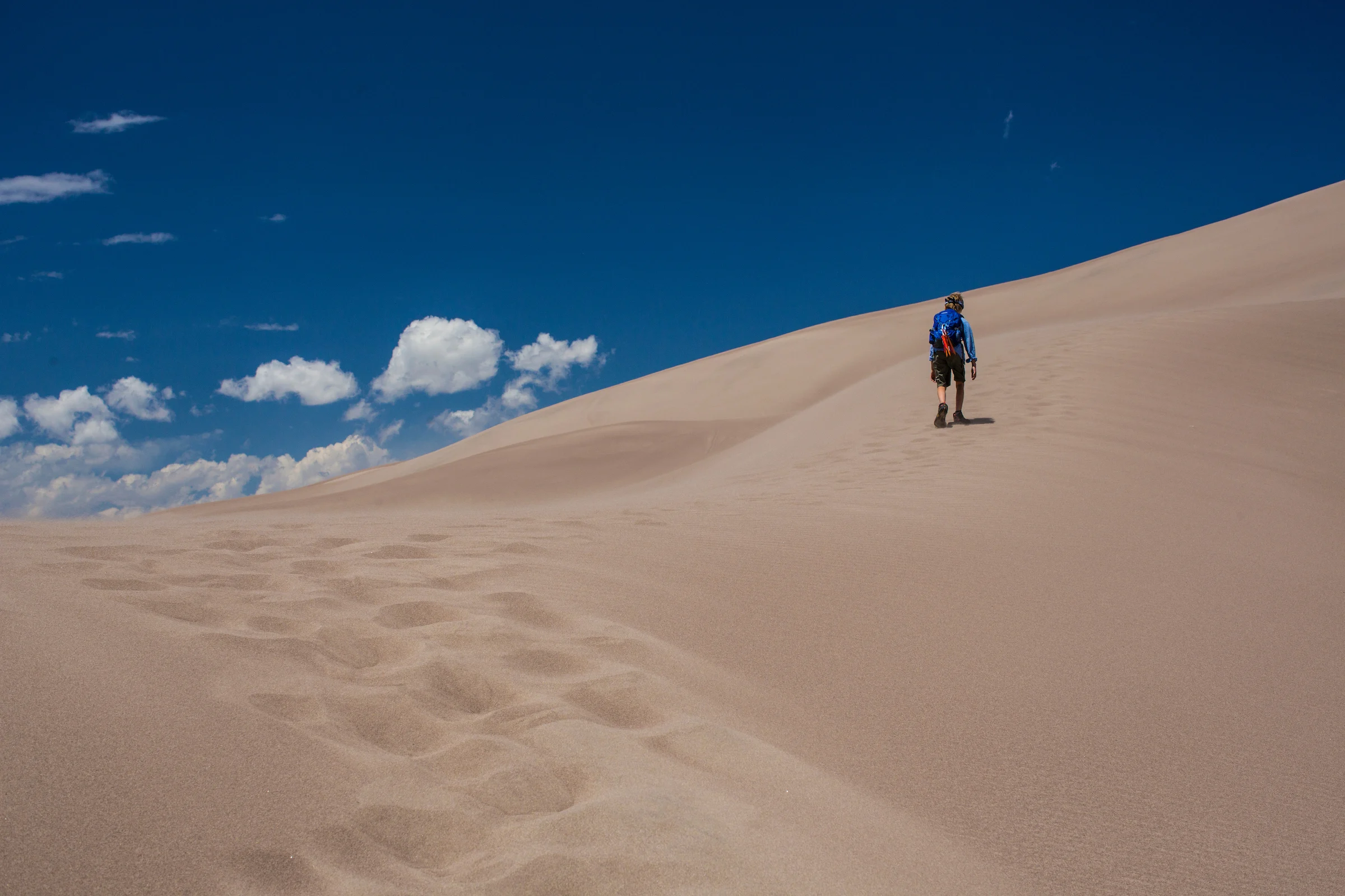 A young man ventures up a sand drift.